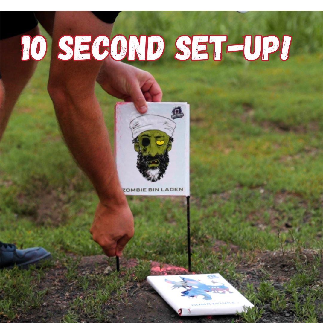 A person is setting up a lawn game by inserting a stand into the ground. One of the game targets, featuring a cartoonish zombie face labeled 