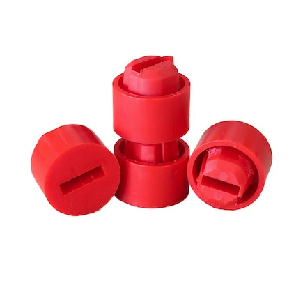 Four red plastic caps, three lying on their sides and one standing upright on top of another, resemble a small target stand. The caps have a flat top with a rectangular cut-out in the center. The background is completely white. These are part of the Hang 'N Hook -Quick Connect 2.0 Upgrade- from Yankee Thunder.